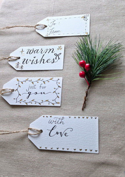 Four hand-lettered gift tags with twine reading To/From, warm wishes, just for you and with love