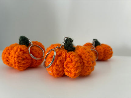 Three orange crochet pumpkin bag charms with green stems and silver key rings