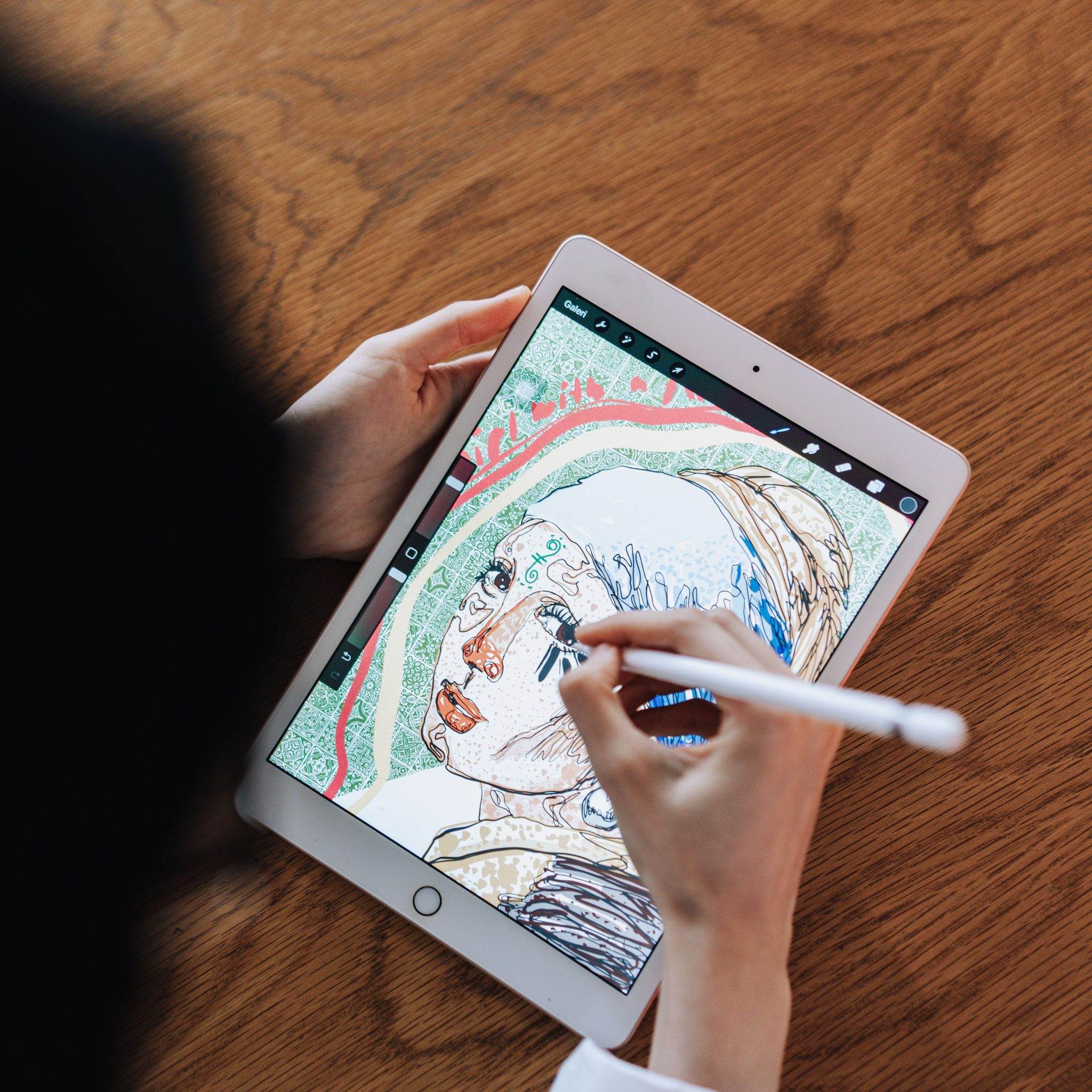 Artist drawing a portrait illustration in Procreate on an iPad with a stylus