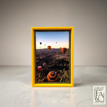 Suwanee Frame & Art hot air balloon landscape print in a bright yellow frame. Cappadocia scene with multiple balloons over canyons.